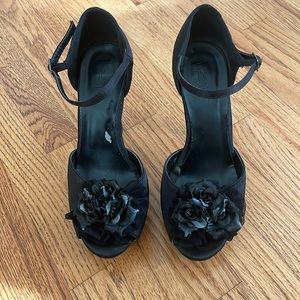 Black platform open toe heels with flower details and ankle straps.
